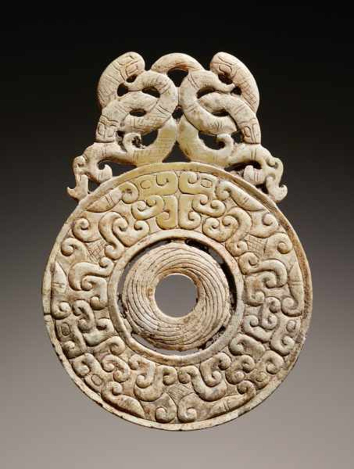 DISC-SHAPED PENDANT WITH DRAGONS Jade. China, Eastern Zhou, 5th - 4th century BCThis small