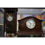 An arched top wooden mantle clock with inlay to sides,