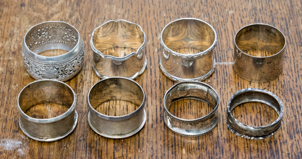 A collection of seven silver napkin rings; together with a white metal napkin ring,