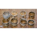 A collection of seven silver napkin rings; together with a white metal napkin ring,