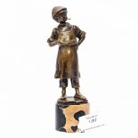 A bronze figure of a boy apprentice wearing an apron, flat cap and smoking a cigarette,