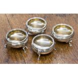 A set of four Victorian silver circular salts, raised on three acanthus capped hoof feet,