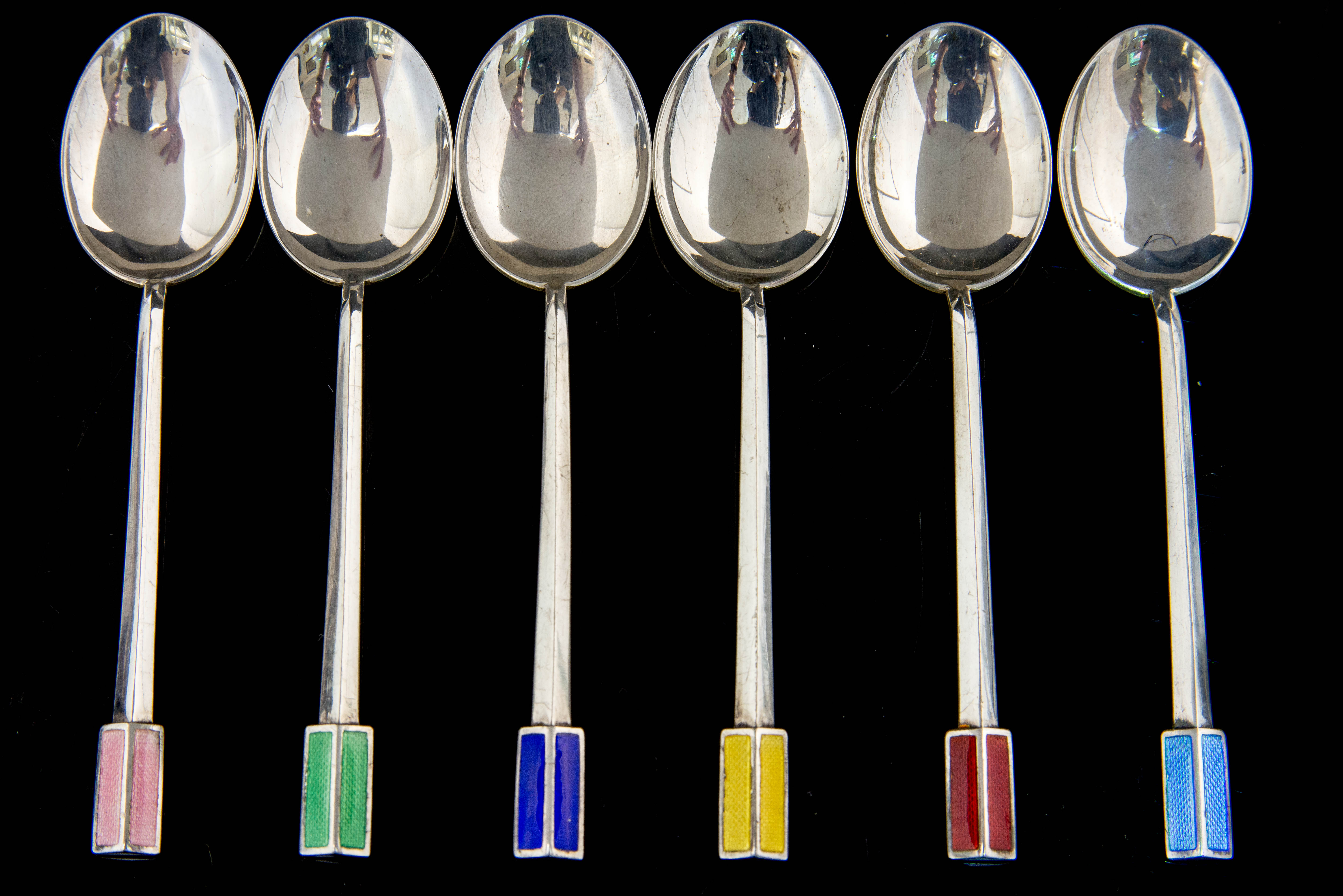 A harlequin set of six Art Deco silver and enamel teaspoons,