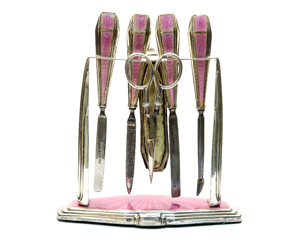 An Art Deco silver and enamelled manicure set and stand, pink guilloche enamel,