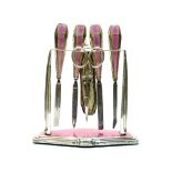 An Art Deco silver and enamelled manicure set and stand, pink guilloche enamel,