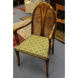 A 1930s armchair in the style fo George Walton, the arched, bisection back with canework panels,