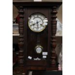 A late 19th Century eight day wall clock having an enamelled chapter dial and black Roman numerals,