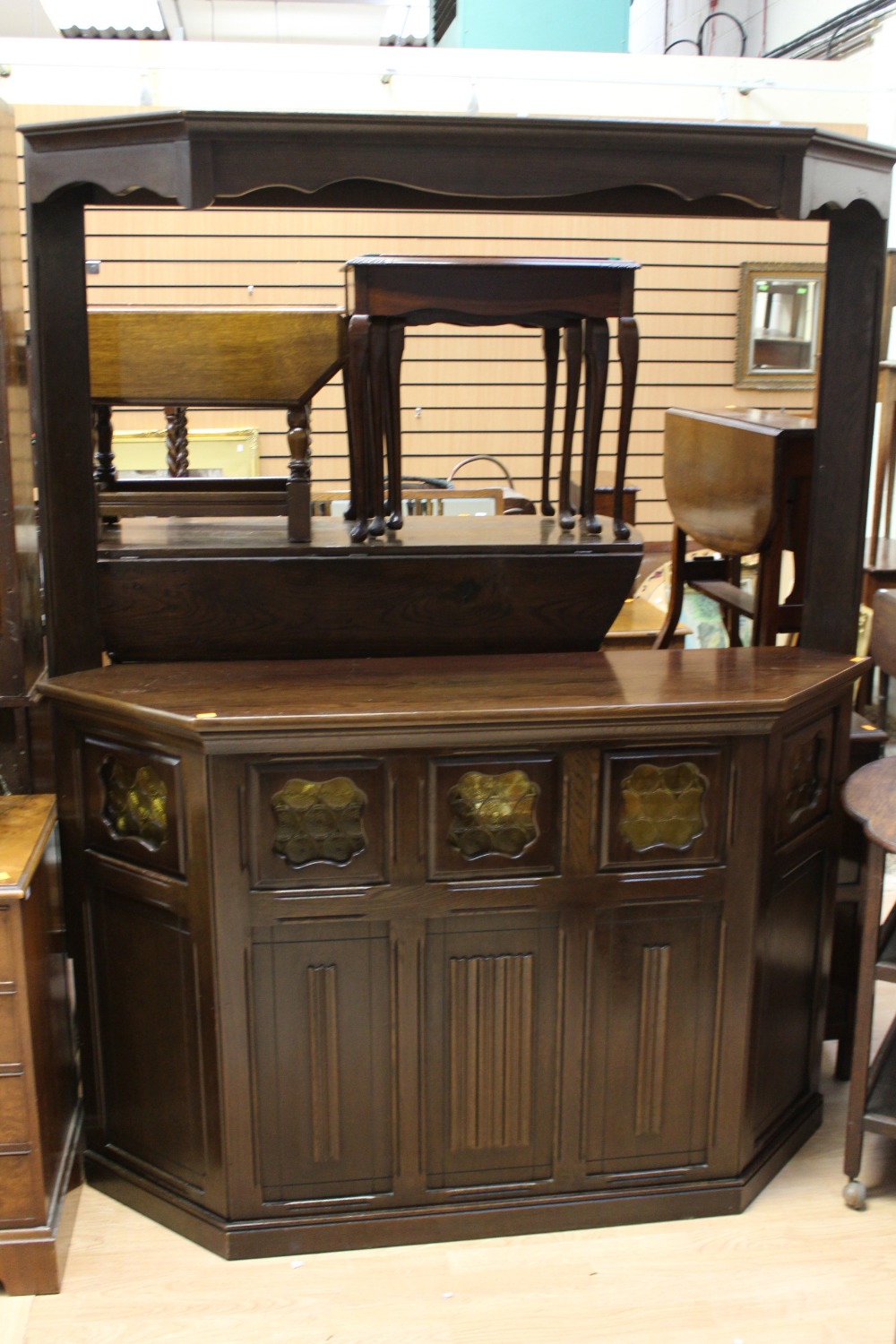 A modern solid oak bar, the upper section with a shaped hood,