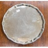 An Elizabeth II circular silver tray standing on four claw and ball feet,