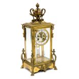 French brass four-glass mantel clock, circa 1890, the upright case with a modelled trophy surmount,