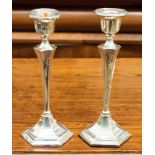 A pair of weighted silver candlesticks, hexagonal form with tapered stems, makers mark indistinct,