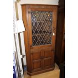 A joined oak two-tier corner unit, the upper section with a lead glazed door,