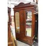 An Edwardian double wardrobe in mahogany, fitted with two mirrored doors and a single drawer,