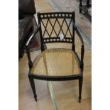 A Sheraton style ebonised cane seated open armchair,