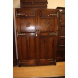 A Jacobean style oak double wardrobe, the two panelled doors opening to reveal a fitted interior,