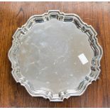 An early 20th century silver salver with pie crust border raised on three feet,