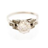 An Art Deco solitaire diamond platinum ring with diamond set shoulders,