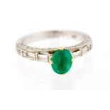 An emerald single stone white gold ring with diamond set shoulders,