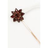A Victorian garnet and rose metal flower head stick pin,