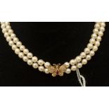 A two row cultured pearl necklace with a ruby and diamond 18ct gold butterfly clasp