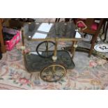 A 1970s brass framed two-tier tea trolley, with large wheels,