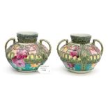 A pair of squat twin handled early 20th century vases, applied with tube lined decoration,