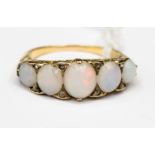 A Victorian five stone graduated opal ring in scroll mount, the oval cabochon opals displaying red,