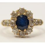 An sapphire and diamond cluster ring with a central oval sapphire surrounded by old cut diamonds