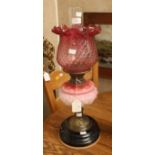 A late Victorian oil lamp with double wick, fitted with Cranberry glass shade,