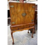 A mid 20th Century walnut veneerer cocktail cabinet, two doors over two drawers,