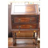 An early 20th Century oak bureau, the fall front over two drawers,