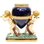 A Minton majolica table centrepiece, 1881, modelled with two putti on a foliate base,