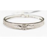 An eighteen carat white gold, round hinged bangle stamped 750 and set with a single white stone,