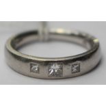 A Diamond three stone platinum band ring, three princess cut Diamonds flush set into a tapered band,