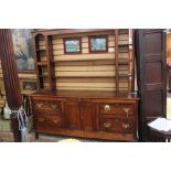 A George III oak dresser and rack, fitted with four long drawers and a central cupboard section,