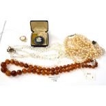 A string of clarified amber beads, a white stone set ring marked 18K, a Wedgwood cameo brooch,