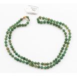 A jade bead necklace, of roughly inform spherical beads, yellow metal clasp, stamped .