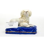 A ceramic figure of a dog and puppy on a blue plinth.