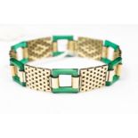 A yellow metal brick link bracelet with alternate green square cut out links,