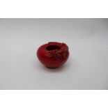 A Chinese sang de boeuf glaze brush pot with recumbent dragon entwined around the rim,