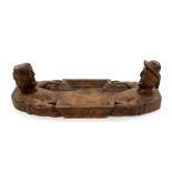 A carved oak folk art tray in the form of a man and a woman reclining in a bath tub,