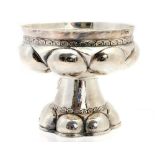 An Arts and Crafts silver pedestal bowl, hand hammered and lobed with embossed foliate banding,