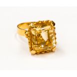 An emerald cut citrine single stone ring set in yellow metal,