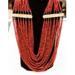 Native art : a dyed coral twenty-four string necklace, set with bone and ebony decoration.