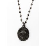 A Victorian Jet pendant with monogrammed initials and leaf decoration on a black enamelled link