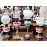 Four assorted table oil lamps with coloured glass reservoirs