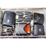 A suitcase with four pairs of binoculars, three leather cases,