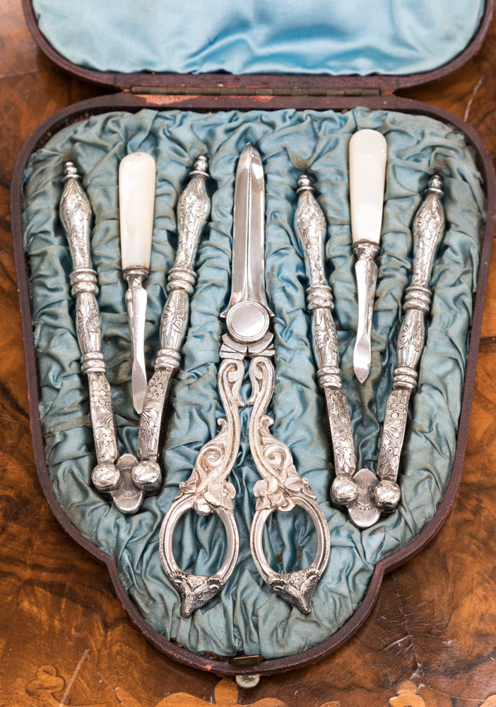 A cased set of white metal table grape scissors,