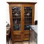 An Edwardian oak glazed bookcase, fitted with two lead glazed doors,