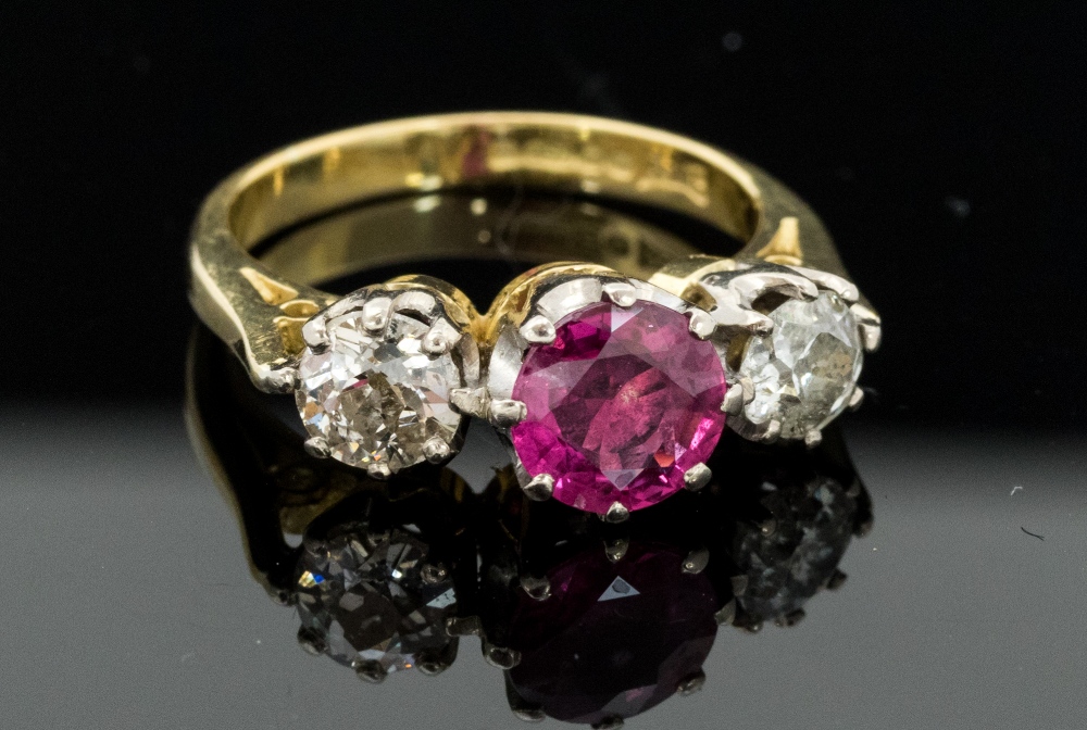 A ruby and diamond three stone 18ct gold ring, the central round mixed cut ruby of approximately 6.